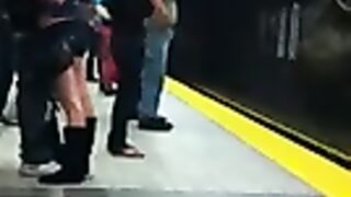 Joven pareja sujeta y besa en la plataforma en el metro.