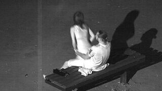 Una chica con un vestido salta sobre la polla de un compañero en un banco del parque frente a una cámara oculta